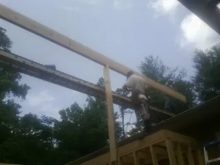 Carpenter setting a ridge beam over a new addition frame — Ice Dam Removal by Roofing Brothers in Emerald Isle