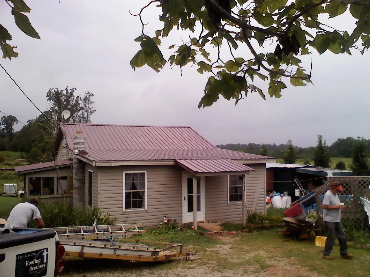 Crew finishing a mauve metal roof on a small farmhouse in Emerald Isle