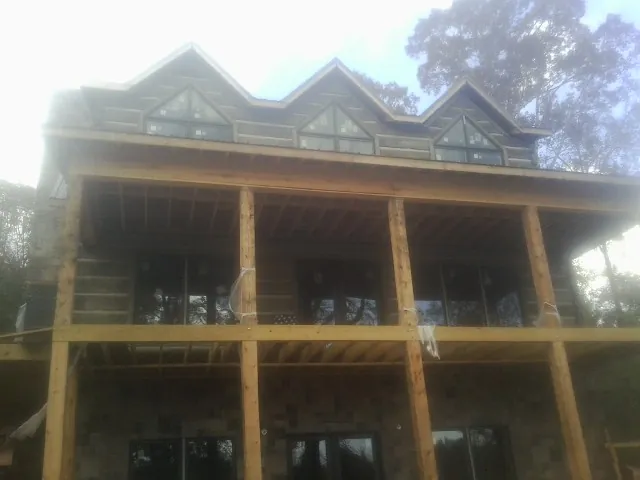 Dormers and porch framing on a large log home under construction — Roof Coating work by our crew in Emerald Isle