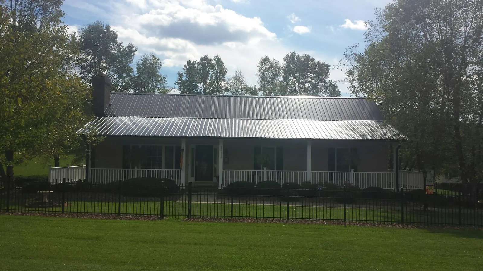 Gray metal roof on a brick ranch with a full width front porch — Gutter Guard Installation work by our crew in Emerald Isle