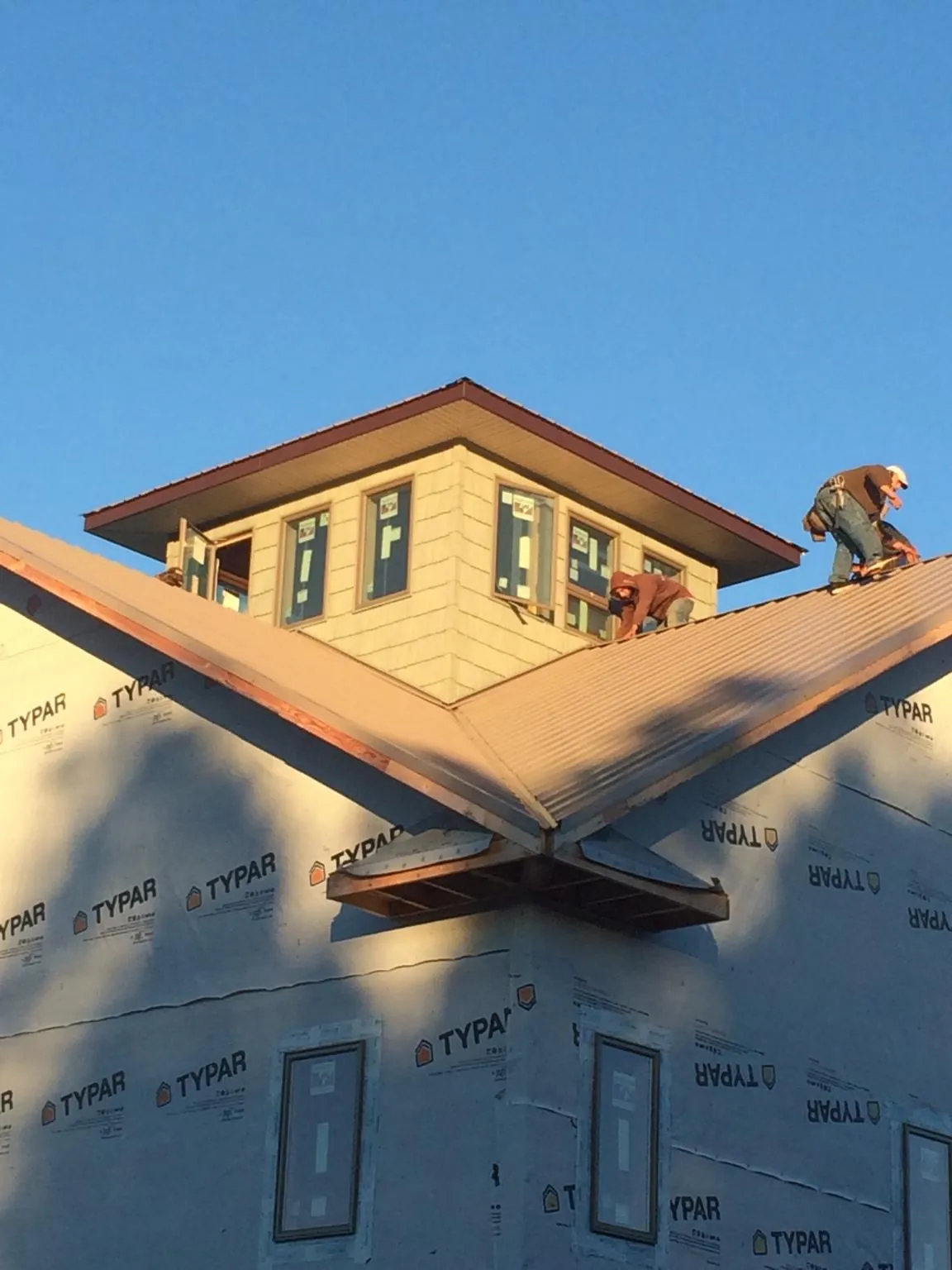 Roofers working around a rooftop cupola on a new metal roof at sunset — Roof Waterproofing in Emerald Isle by Roofing Brothers